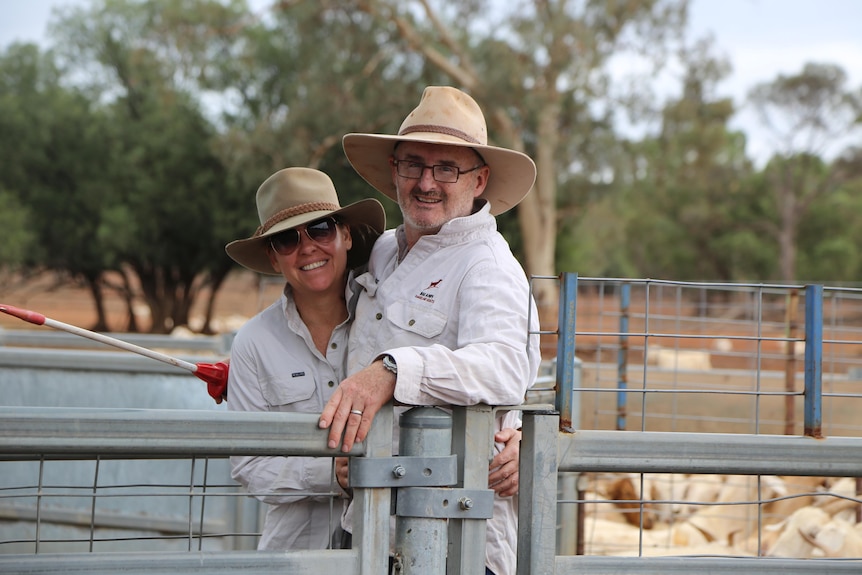 A man and woman in khaki coloured shirts stand together.