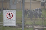 Riot police seen through a metal fence