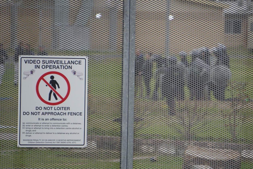 Riot police seen through a metal fence