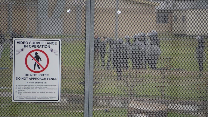 Riot police seen through a metal fence