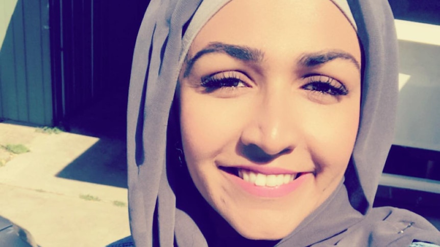 A photo of Anam Javed wearing a grey hijab and smiling.