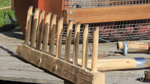 Handmade timber garden rake resting on an outdoor table