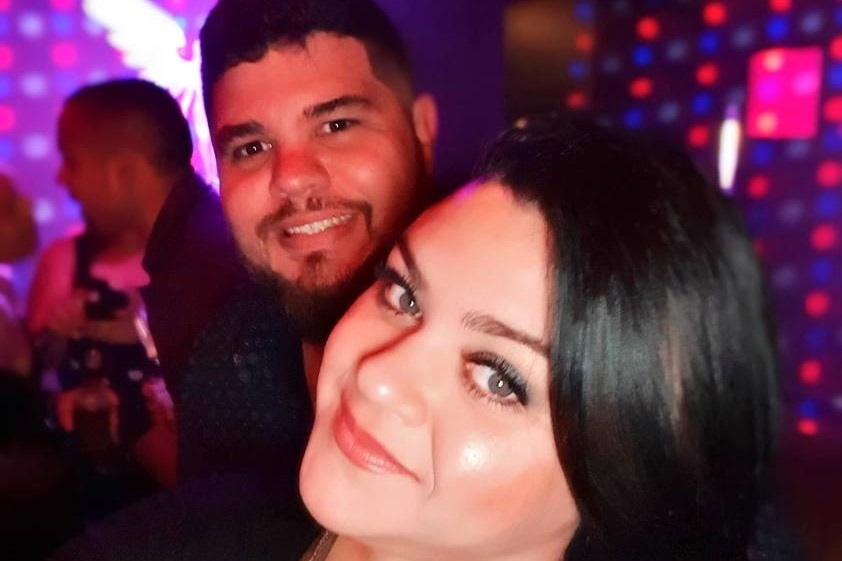 Two people smiling at the camera in a night club setting.