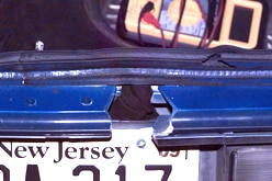 A hole is carved in the boot of a blue car with a New Jersey licence plate.