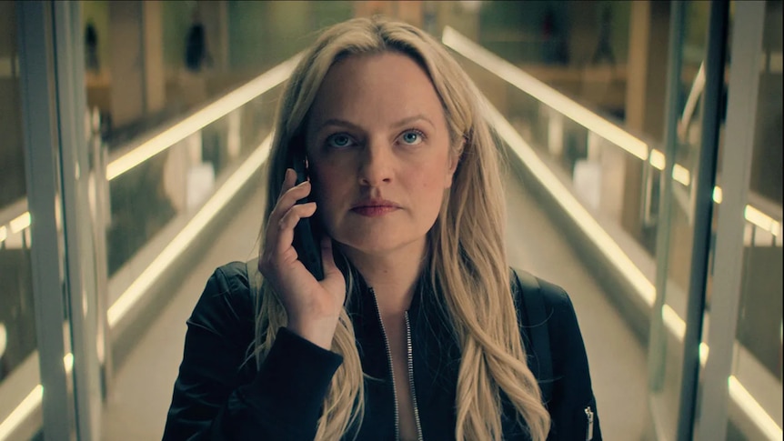 Elisabeth Moss looking very serious, a mobile phone to her ear