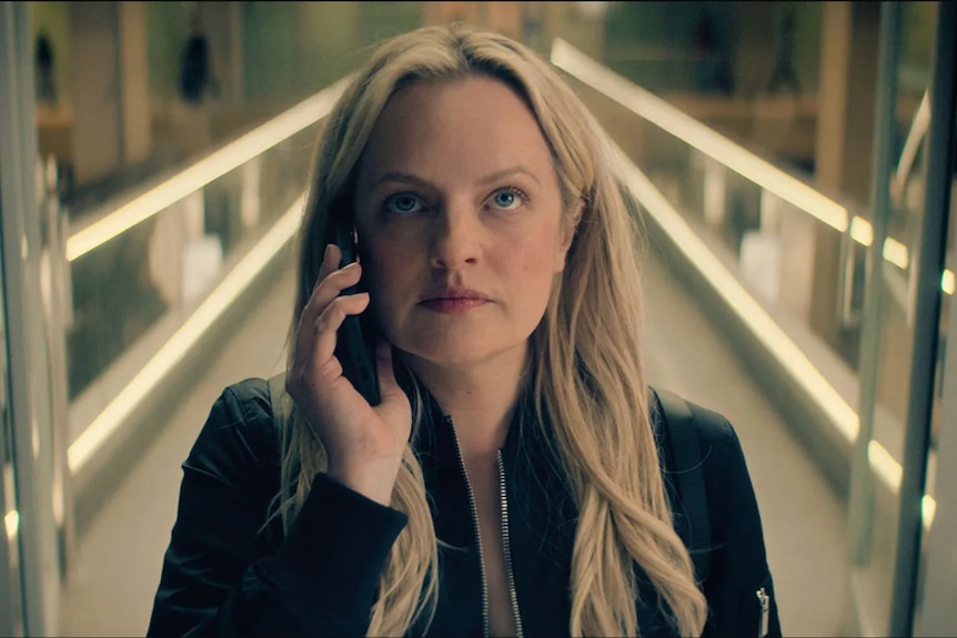 Elisabeth Moss looking very serious, a mobile phone to her ear