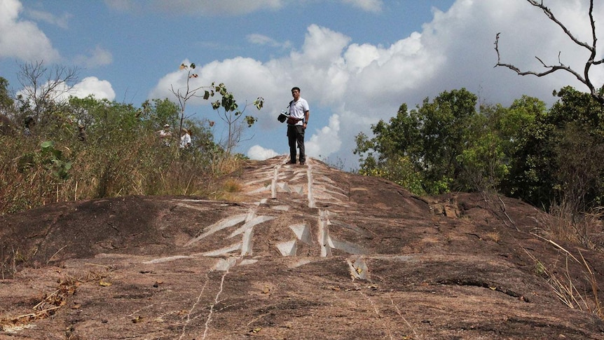 a man standing atop a carved hill