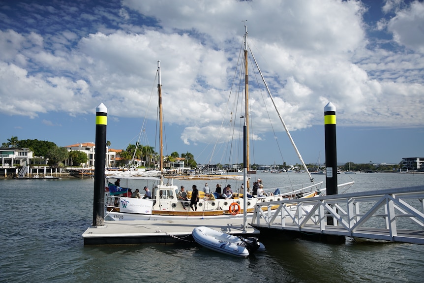 A tall ship at a jetty, with people on board.