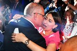 Scott Morrison kisses Gladys Berejiklian, while surrounded by party supporters filming on their phones.