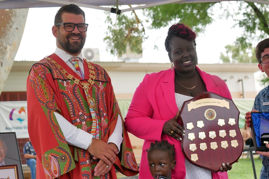 A smiling woman is given an award by a man in mayoral robes.
