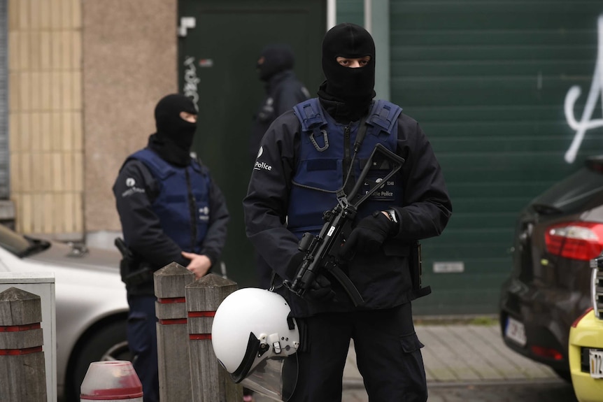 Police officers stand guard in Molenbeek district, Brussels