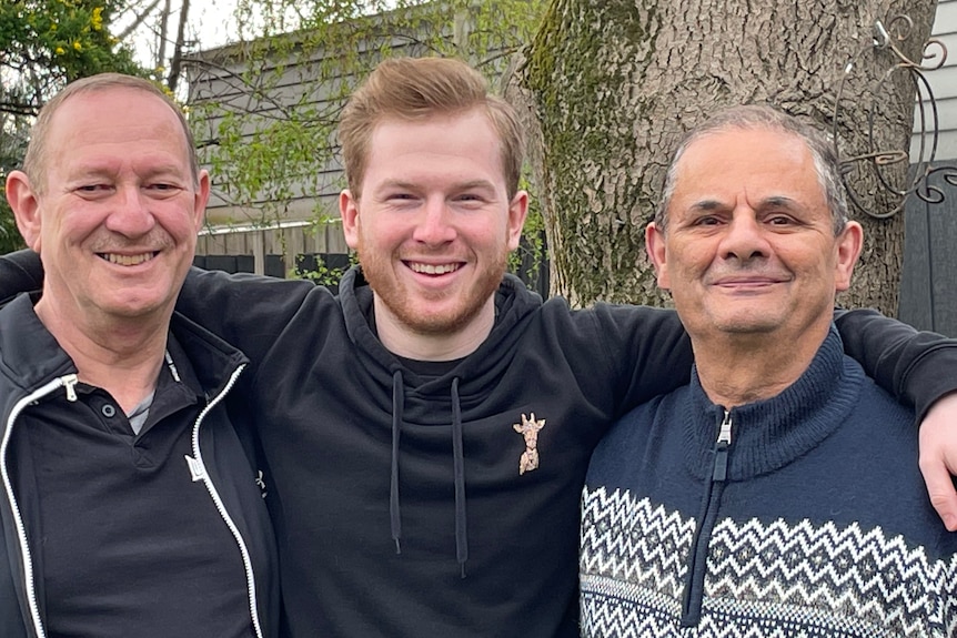 Recent photo of Kyle and foster dads standing together outside