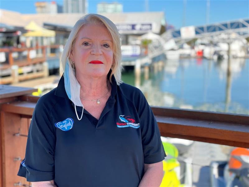 A woman with blond hair stands at a marina
