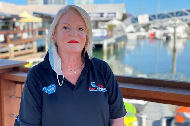 A woman with blond hair stands at a marina