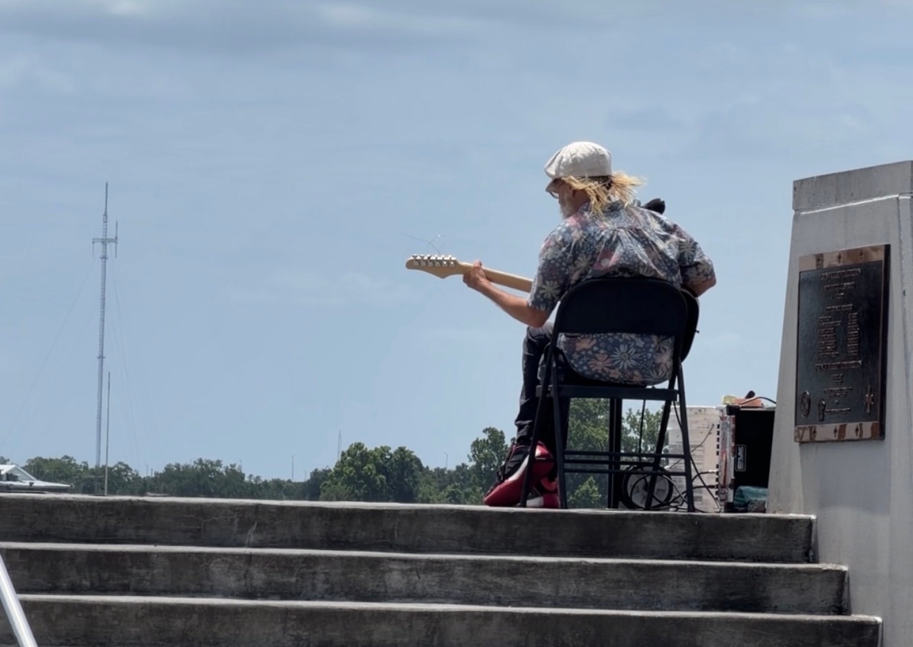 Un hombre toca la guitarra y mira hacia otro lado de la cámara.