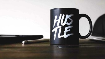 A black mug with the word "hustle" written on it.