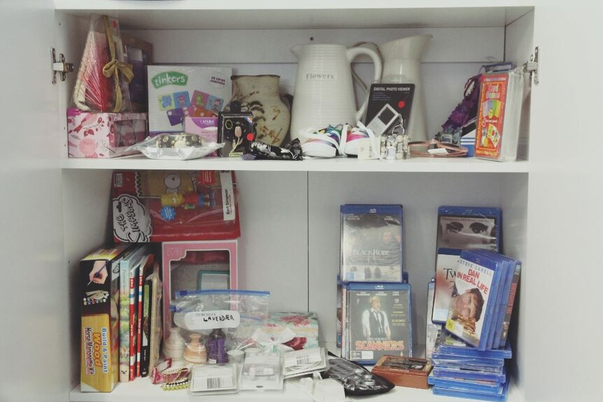 A range of gifts in a cupboard including children's toys, vases, DVDs and board games