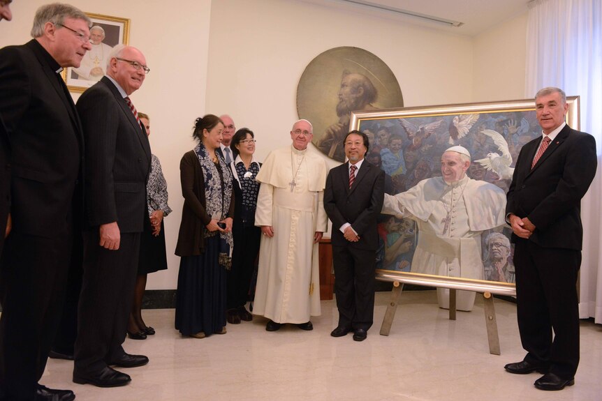 Shen pose in the front of the Pope Francis's portrait