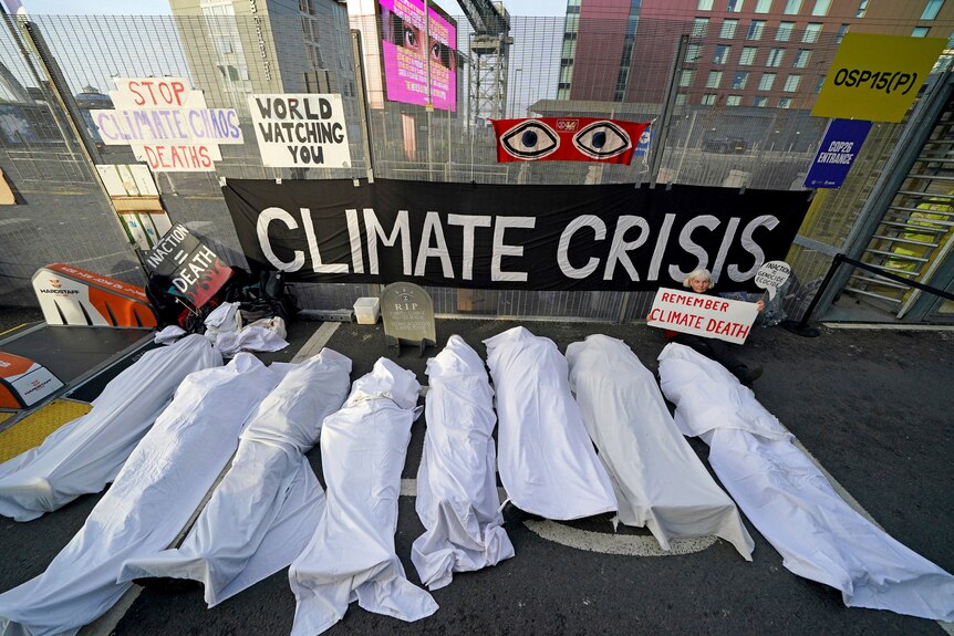 Climate activists dressed as shrouded bodies protest near the venue for COP26