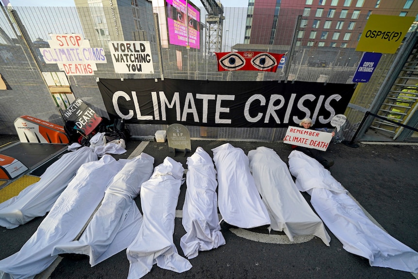 Climate activists dressed as shrouded bodies protest near the venue for COP26