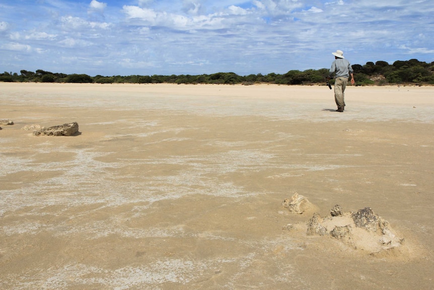 David Paton walks along a sandy dried lagoon