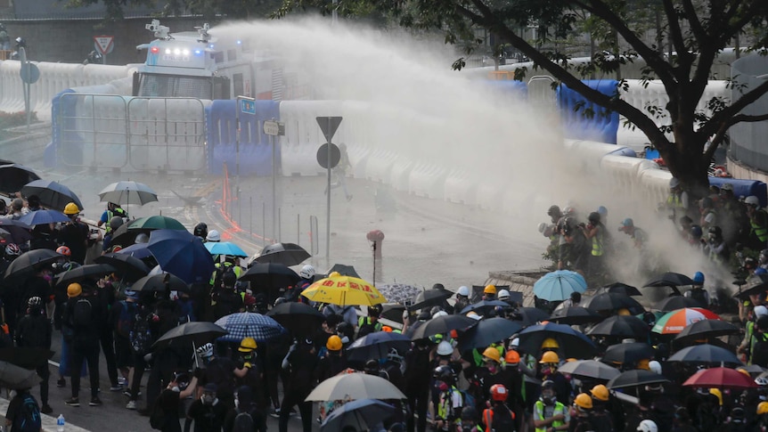 Anti-government protesters are sprayed by a water cannon during a demonstration