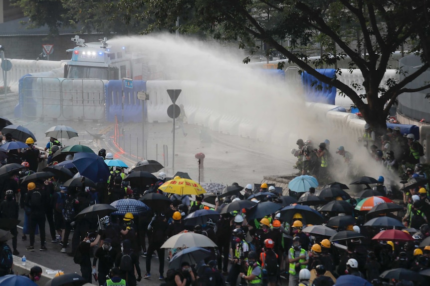 Anti-government protesters are sprayed by a water cannon during a demonstration