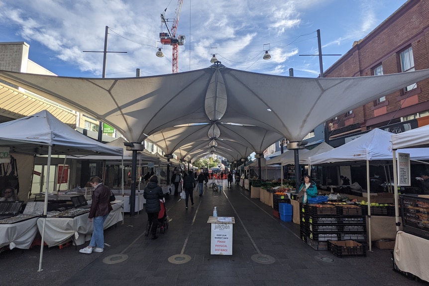 Market stalls lining a footpath, each with a material awning covering