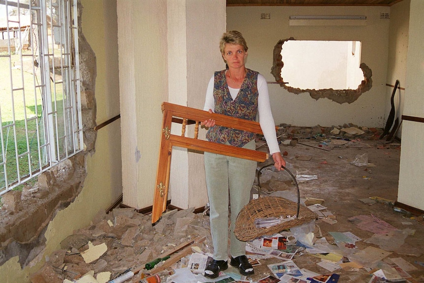 Zimbabwean farmer's wife Judith Swan holds a piece of broken furniture in her homestead