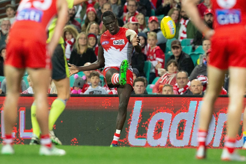 An AFL player kicks a drop punt for goal - and scores.