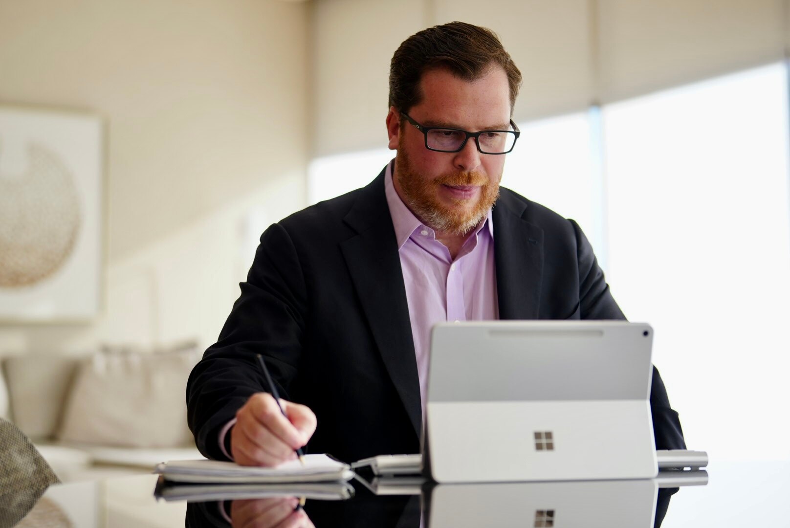 A photo of Saul Kavonic looking at a laptop and writing