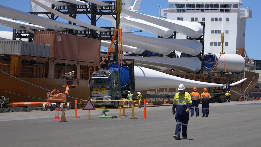 A large ship docked at a port with cargo being unloaded.