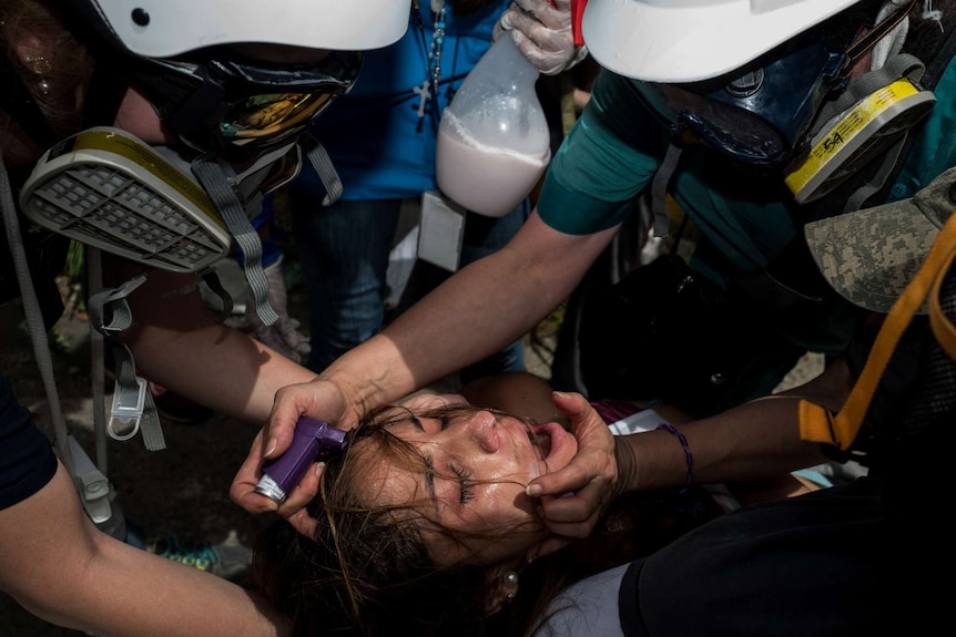 A woman is helped by men in masks