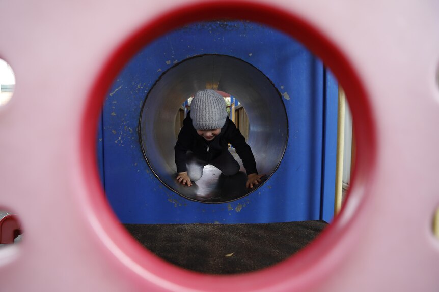 A child crawls through play equipment at a child care facility.