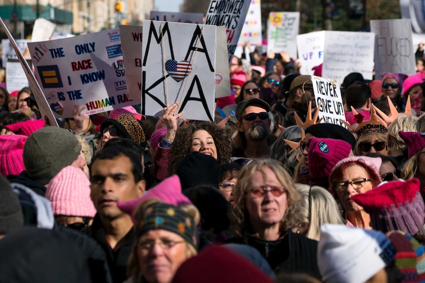 A group of women pack into Central Park,  wearing pink knitted hats and hold up signs