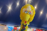 A large yellow bird costume wearing a tie
