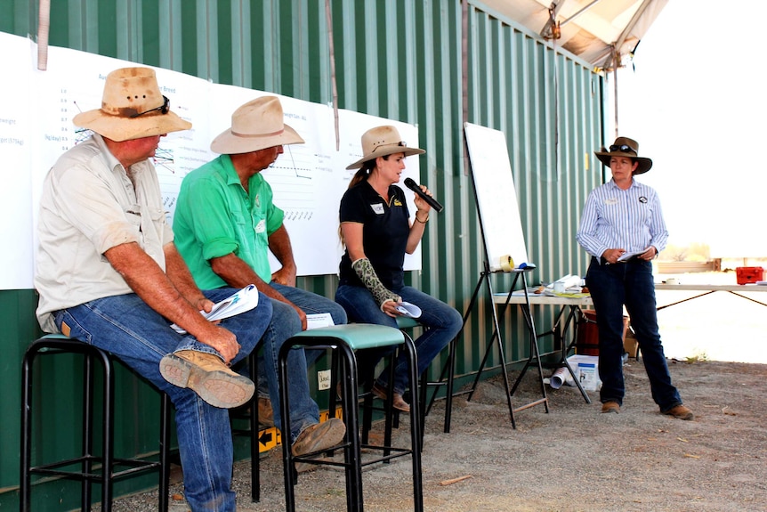 Three pastoralists sit on stools and discuss issues with convenor.