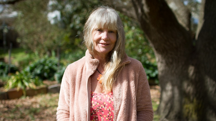 Rachel Stewart standing in her back yard beside a large tree.