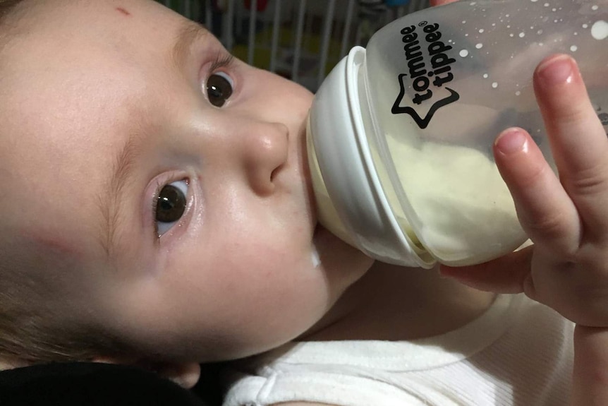 A photo of an infant being bottle-fed.