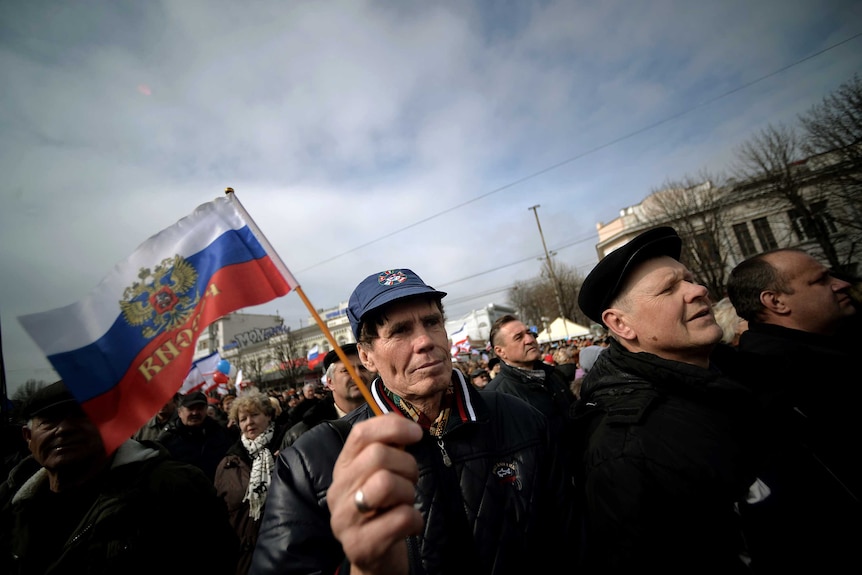 Man hold Russian flag at rally in Simferopol's Lenin Square.