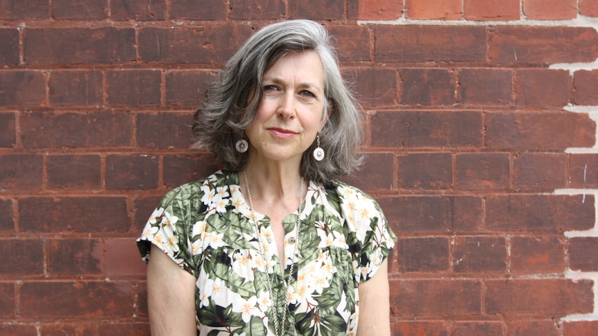 Naomi Halpern stands in front of a brick wall.