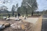 eight black silhouettes of people standing in circle with rocks around them