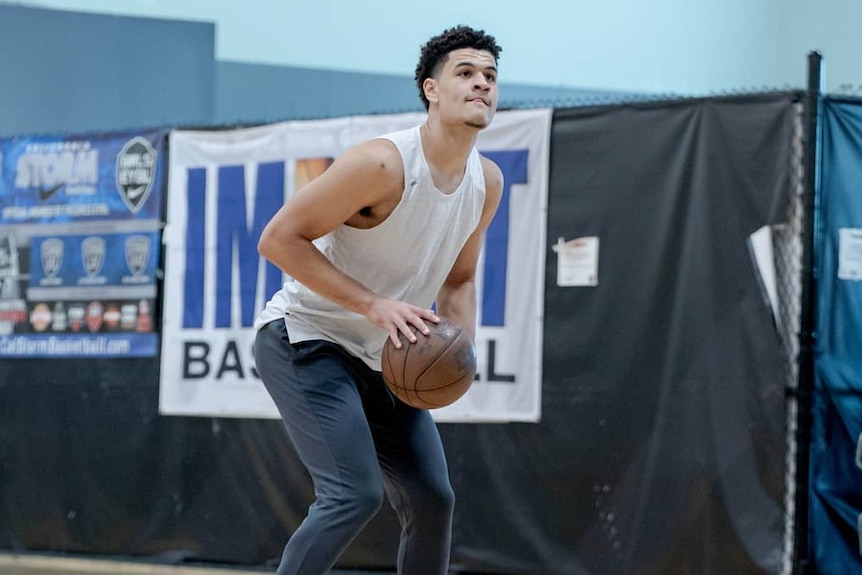 Josh Green bends forward with both hands on a basketball preparing to shoot