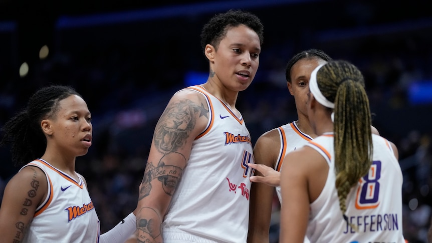 Wearing white, Brittney Griner reacts with her teammates in WNBA game