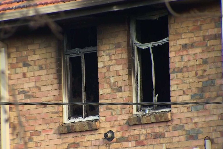 Two broken windows ringed with black soot.