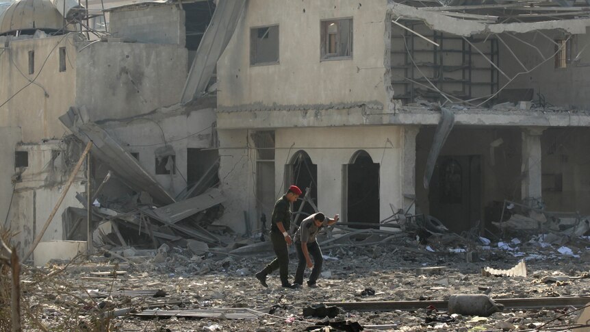 Members of Hamas survey the damage to a Hamas security site in Gaza City