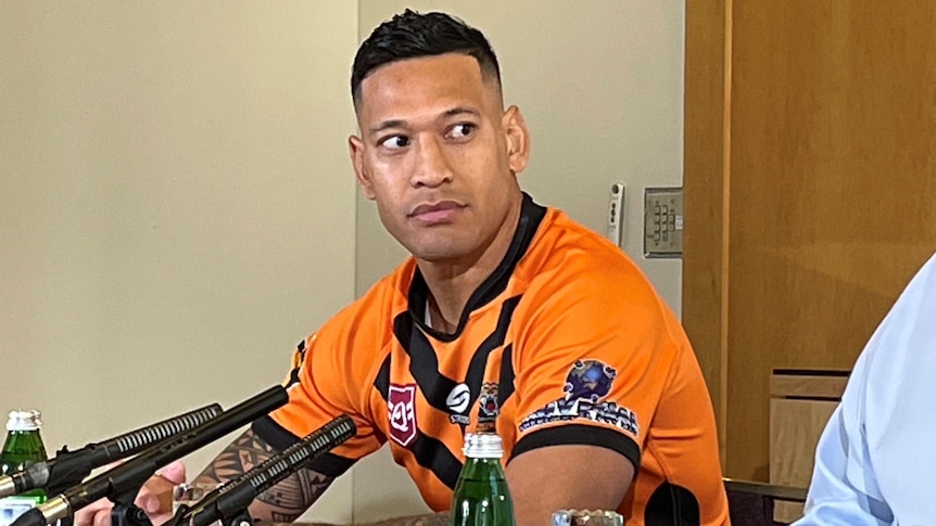 Man sitting behind microphones during an press conference.