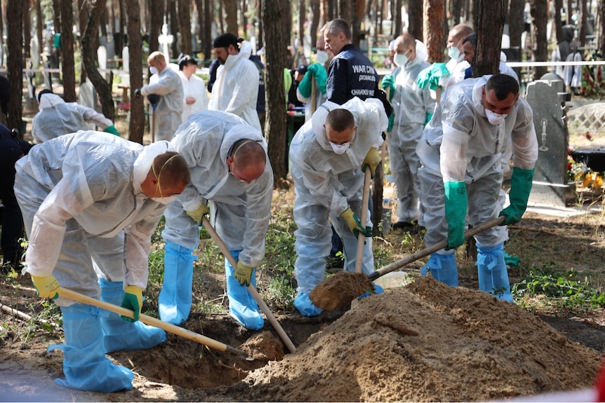 Four men in protective clothing digging.