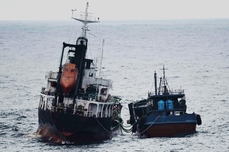 Two ships close to each other at sea, connected by pipes
