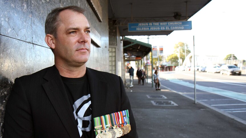 Former Australian Army Captain Jason Scanes stands in a street.
